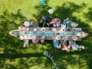 Top view of people at summer garden party in beautiful garden. BBQ family gathering, with a set...