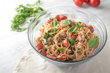 Mediterranean party salad from spaghetti with tomatoes, arugula, mozzarella, olives and basil in a...