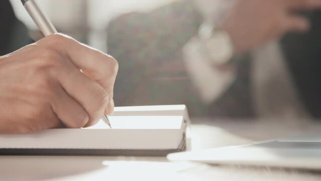 Close up side slowmo of female hand writing with pen in diary in office on sunny day
