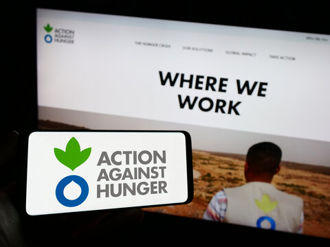 Stuttgart, Germany - 10-09-2023: Person holding mobile phone with logo of humanitarian organization Action Against Hunger in front of web page. Focus on phone display.