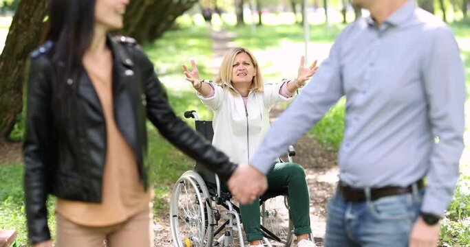 Woman in wheelchair screaming at trail of couple leaving in front of her in park 4k movie slow motion. Relationship difficulties for people with disabilities concept