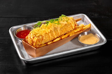 Deep fried corn dog topped with mozzarella served with fries and sauces