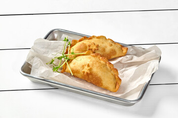 Savory puff pastry turnovers filled with meat and mushrooms garnished with microgreens