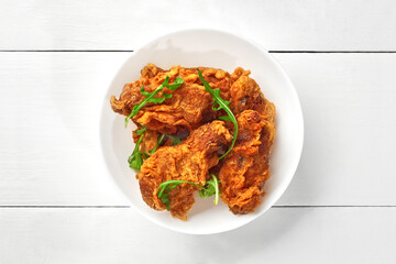 Deep-fried chicken wings in spicy crispy batter with arugula