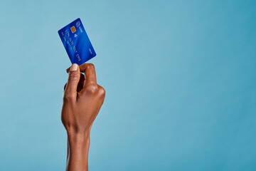 Black female hand holding credit card isolated on blue background