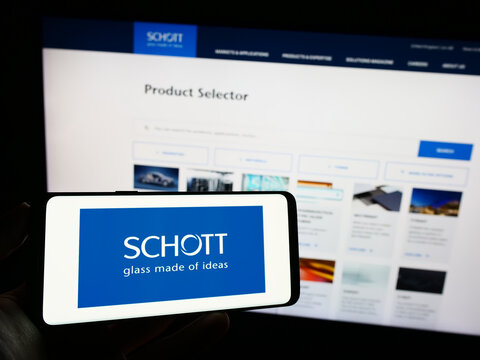 Stuttgart, Germany - 10-13-2023: Person holding mobile phone with logo of German glass manufacturing company Schott AG in front of business web page. Focus on phone display.