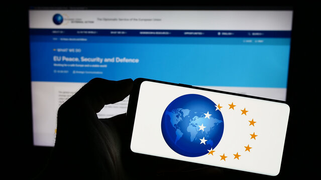 Stuttgart, Germany - 10-16-2023: Person holding mobile phone with logo of EU institution European External Action Service (EEAS) in front of web page. Focus on phone display.