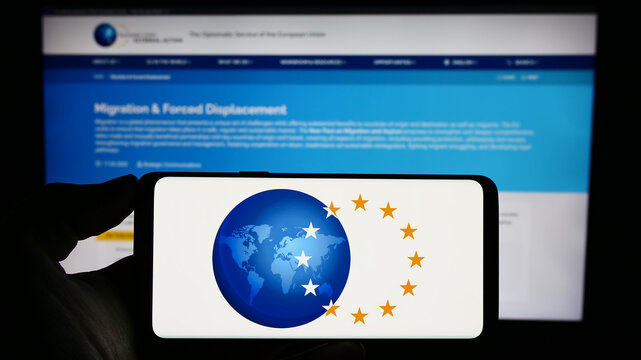 Stuttgart, Germany - 10-16-2023: Person holding cellphone with logo of EU institution European External Action Service (EEAS) in front of webpage. Focus on phone display.