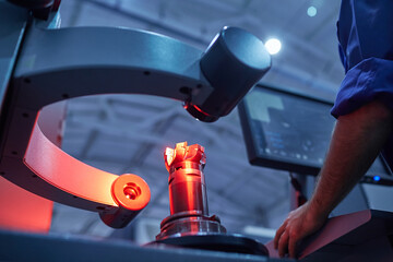 a worker checks the quality of a tool on special equipment using infrared sensors