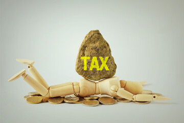 Wooden mannequin lying under heavy boulder with the word Tax - Concept of being crushed by the weight of taxes