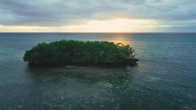 Siquijor Island, Philippines. Aerial drone view orbiting around an islet close to shore. Vibrant colorful clouds at dusk.