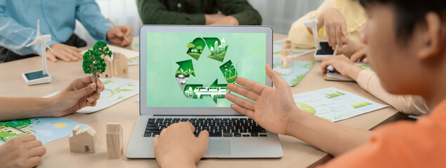 Recycle sign displayed on green business laptop while business team presenting green design to...
