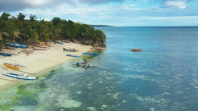 Paliton beach, Siquijor Island, Philippines. Slow aerial drone view. Local filipino fishermen. Colorful fishing boats in clear turquoise water.