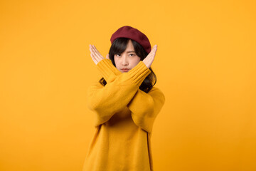 Young Asian woman in her 30s, wearing a yellow sweater and red beret, signifies a firm prohibition...