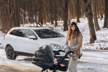Obraz premium mother and daughter are walking in the winter park against the background of cars