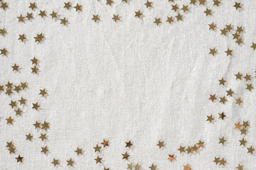 Golden star confetti frame on neutral beige linen cloth background. Minimalist aesthetic New Year...