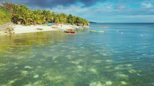 Paliton beach, Siquijor Island, Philippines. Slow aerial drone view at low altitude. Local filipino fishermen. Colorful fishing boats in clear turquoise water.