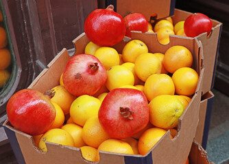 Oranges and pomegranates in a cardboard box at a street market