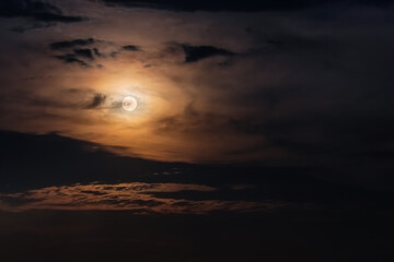 Full Moon surrounded by clouds in the night sky. Moonlight on a cloudy night