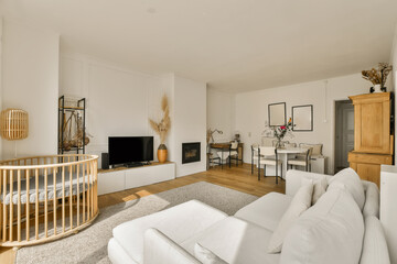 a living room with a baby cribt in the corner and an entertainment center on the wall is white