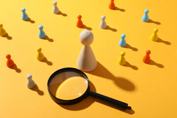 Magnifying glass and figurines on yellow background