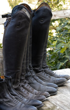 schmutzige alte Reitstiefel Leder bereit zur Reinigung aufgereiht auf einem alten Holztisch