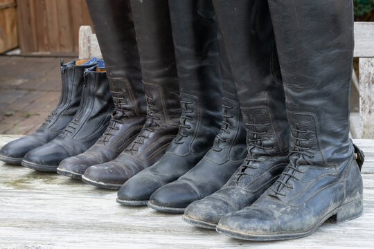 schmutzige alte Reitstiefel Leder bereit zur Reinigung aufgereiht auf einem alten Holztisch