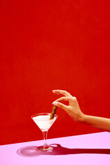 Traditional original drink. Glass with martini decorated with olives isolated over red background. Salty taste of appetizer. Concept of alcohol drinks, party, holidays, bar. Poster. Copy space for ad
