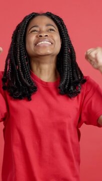 Happy african woman celebrating while raising arms