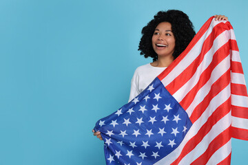 4th of July - Independence Day of USA. Happy woman with American flag on light blue background,...