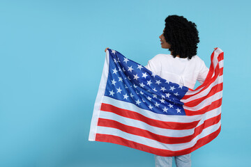 4th of July - Independence Day of USA. Happy woman with American flag on light blue background,...