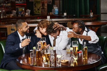 happy multiethnic male friends hugging during bachelor party in bar, tequila, whiskey and beer
