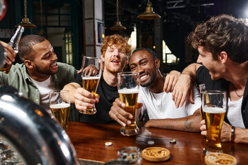 four happy multiethnic men holding glasses of beer during bachelor party, male friends in bar