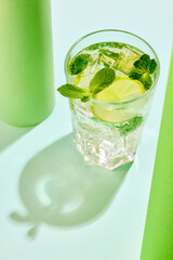 Poster. Top view photo of lemonade with lime slices and mint against vibrant contemporary colored studio background.
