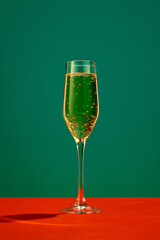 Sparkling champagne glass amidst vibrant red and green studio backdrop, evoking a sense of festive merriment and joy.