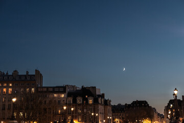 Fototapeta na wymiar Toits de Paris la nuit avec la lune