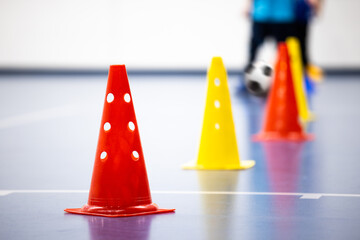 Training Cones on Sports Hall. A row of Red and Yellow Football Soccer Practice Cones. Kids Attending Futsal Drill on Wooden Floor