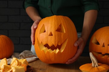 Woman with carved pumpkins at wooden table, closeup. Halloween celebration