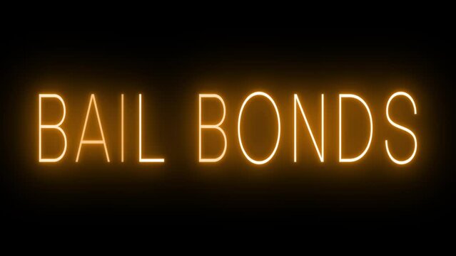Flickering orange retro style neon sign glowing against a black background for BAIL BONDS