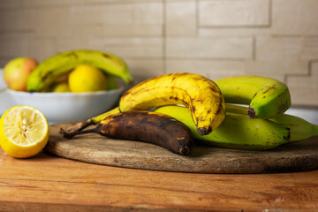 three bananas from overripe to green on a gray background