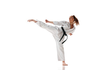 Attractive woman in white sport karate uniform with black belt training in action against white studio background. - Powered by Adobe