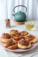 Many tasty cinnamon rolls on white table, closeup. Space for text