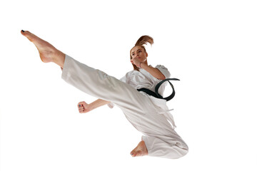 Rear view. Woman professional karate fighter jumping and performing kick in action isolated over...
