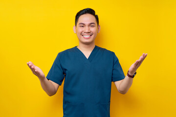 Professional young Asian male doctor or nurse wearing a blue uniform standing confidently and...