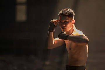 Young muay thai boxer man guarding up and training boxing in the dark