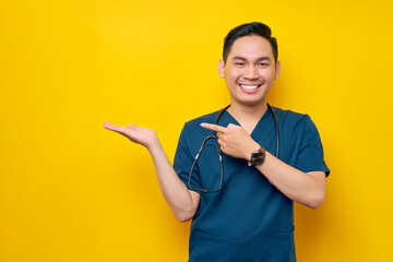 Smiling professional young Asian male doctor or nurse wearing a blue uniform showing copy space...