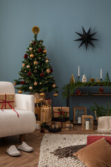 Cozy and stylish christmas living room interior with design armchair, christmas tree, gifts, wooden laterns, blue wall, red pillow, christmas balls decoration. Santa claus is coming. Template.