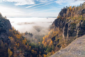 Picturesque mountain landscape in autumn. Blue sky, fog, yellow trees. Saxon Switzerland, Germany, near Dresden - obrazy, fototapety, plakaty