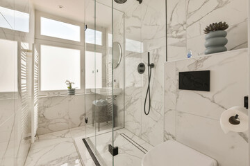a modern bathroom with white marble walls and flooring the shower is surrounded by a glass door that leads to a large window