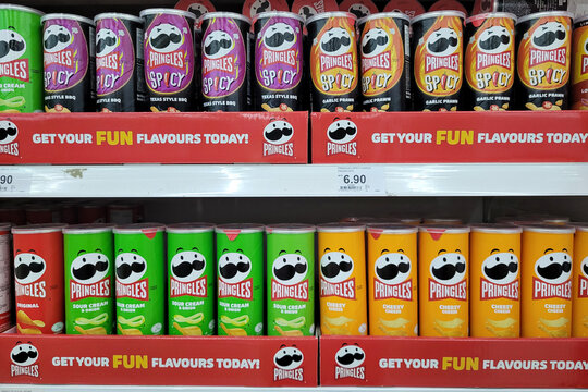 PENANG, MALAYSIA - 12 OCT 2023: Row of Pringles Snack on store shelf in Giant Grocery store. Pringles owned by the Kellogg Company, brand of potato snack chips sold in 140 countries.